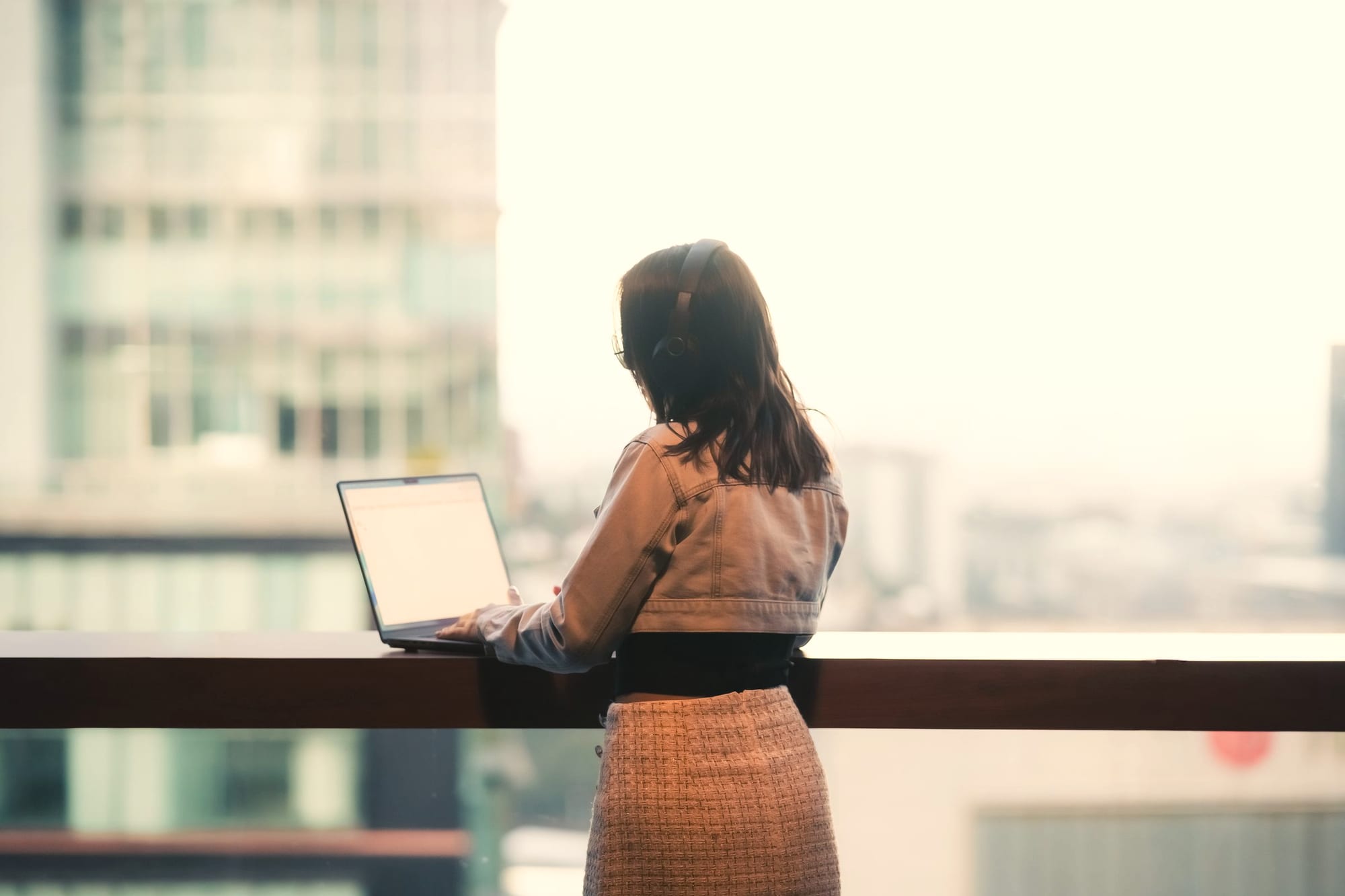 A professional working on a laptop from a balcony overlooking a city skyline