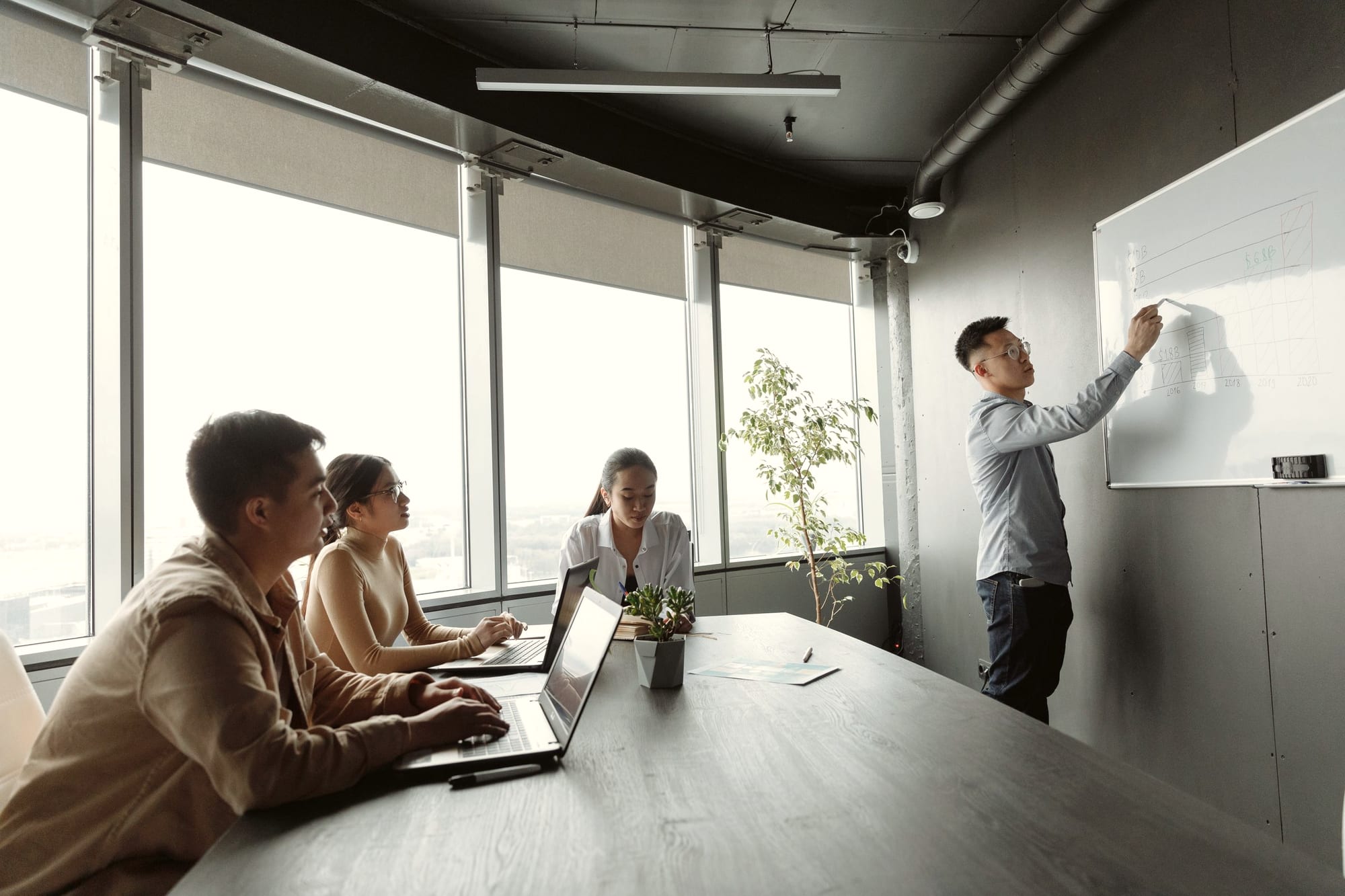 Coworkers gathered around a whiteboard as a colleague presents a chart.